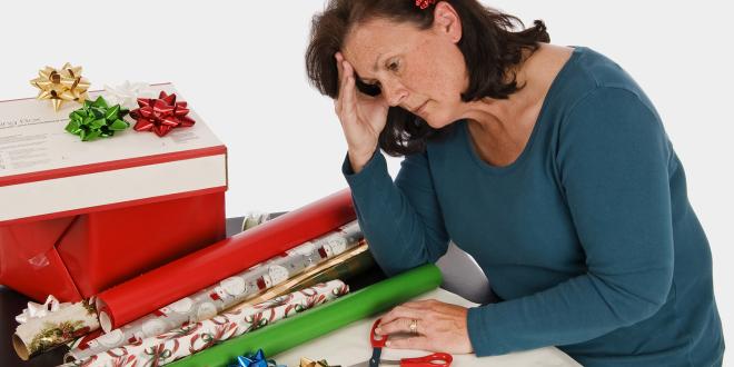 A very tired woman slouching in front of a pile of gift wrapping paper