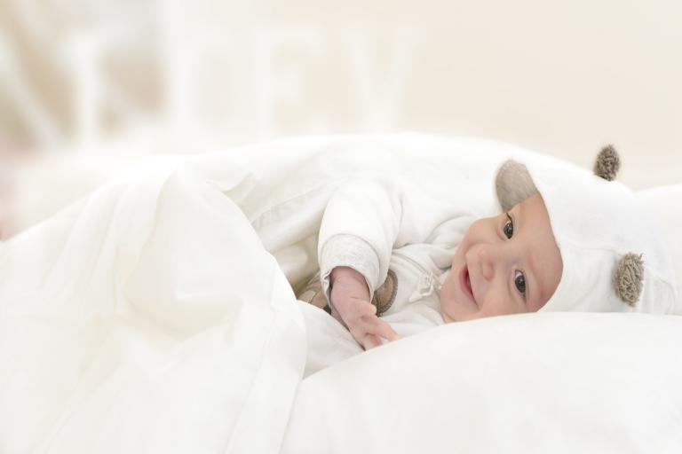 A happy baby smiling snuggled in a white blanket